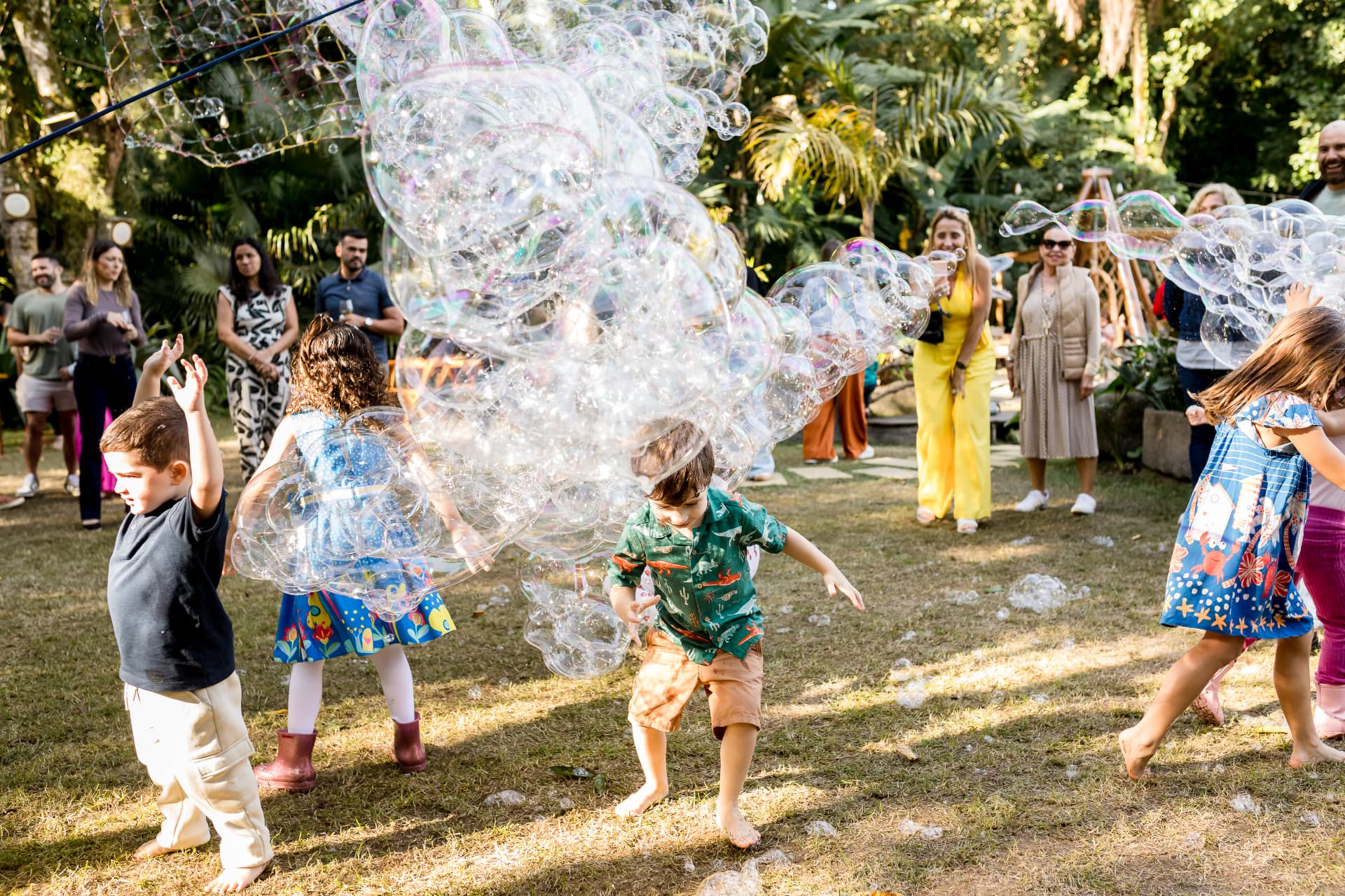 Crianças brincando com bolhas de sabão no gramado do Jamboo